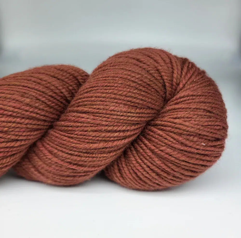 Rust-orange skein of thick, plied yarn coiled for knitting or crocheting